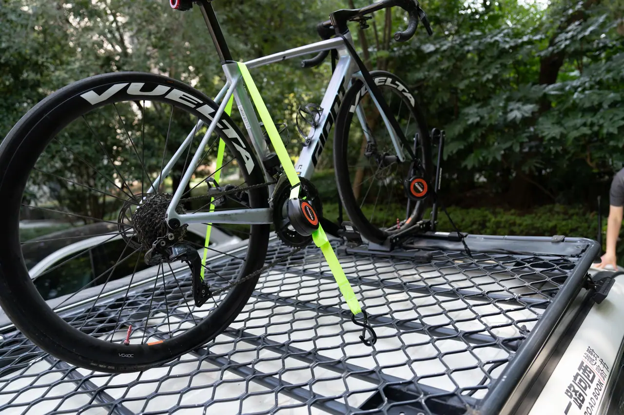 Rouleau d’arrimage à rappel automatique fixant un vélo à un filet de plateau de camion