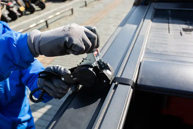 Self-retracting ratchet strap clipped to a boat deck rail